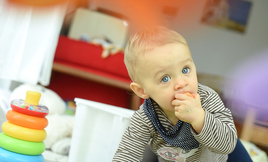 Baby mit Spielzeug im Mund
