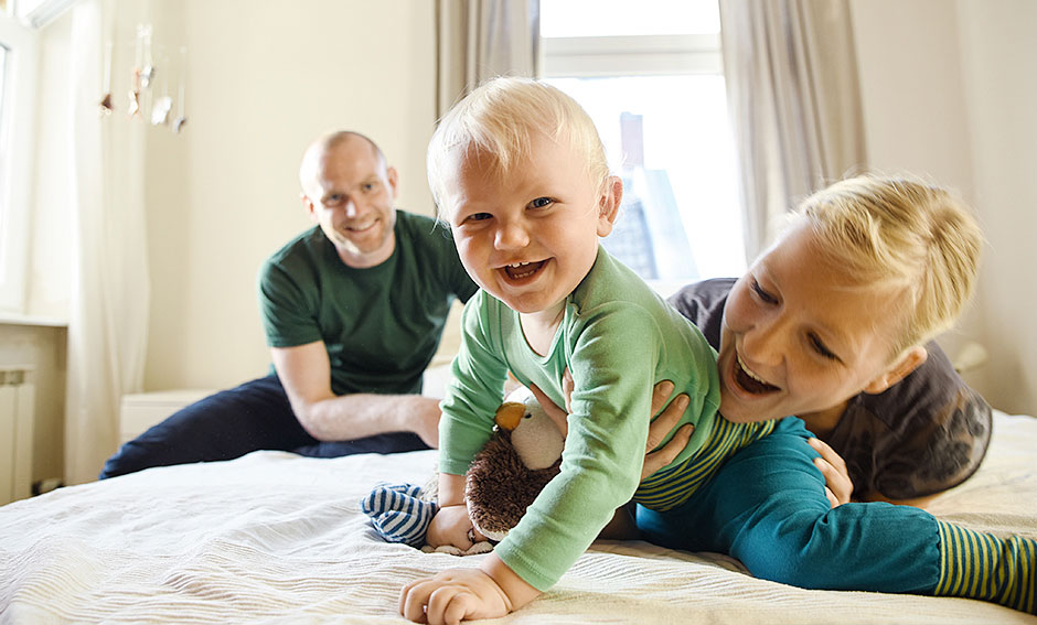 Familienfoto zuhause auf dem Bett Junge blickt in Kamera, Familienfotograf Berlin