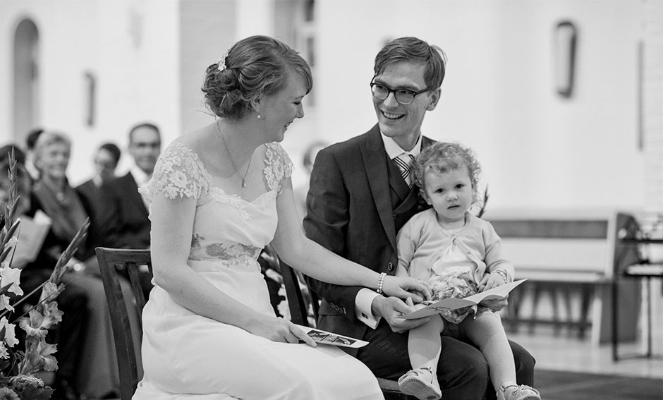 Hochzeitsfoto Kirche Brautpaar mit Kind lachen