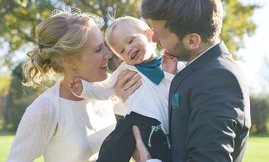 Hochzeitsfoto Hochzeitspaar gluecklich mit Kind auf dem Arm