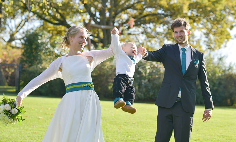 Hochzeitsfoto Hochzeitspaar gluecklich mit Kind im Garten